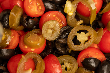 Vegetable salad of tomatoes, black olives and pickled Jalapeno pepper, seasoned with olive oil.