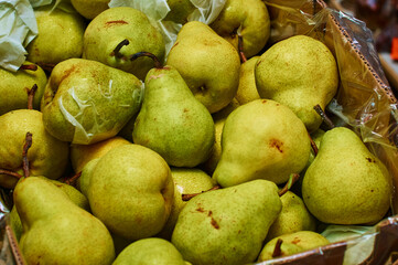 Green pears in a box at a farmers' market. Fresh organic fruits for sale on the counter. Close up