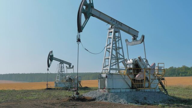 Pumping rigs extracting oil from an oil well in vast oil field. Oil Industry Equipment.