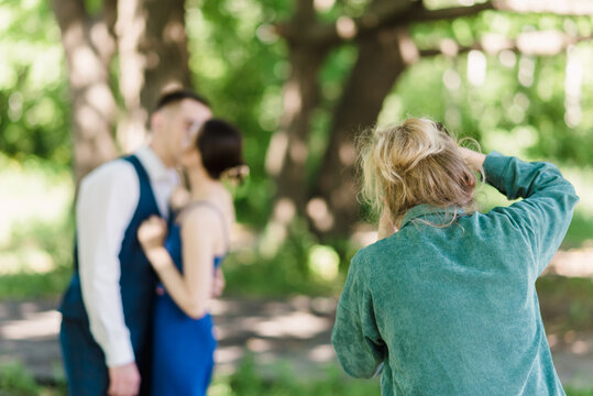 A wedding photographer photographs a couple in nature on a sunny day