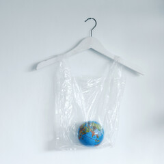 A globe earth on plastic bag hanging on the white wall background. The concept of World Environment Day.