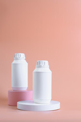 White unbranded plastic medicine bottles mockup for vitamins or pills on pink and white podium against pastel background.