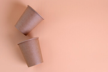 Disposable paper coffee cups on pastel background. Eco-friendly hot drink containers top view.