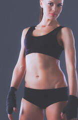 Muscular young woman standing on gray background