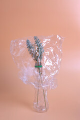 Flowers under a transparent plastic. Polyethylene Film. Plastic pollution and environmental problem.
