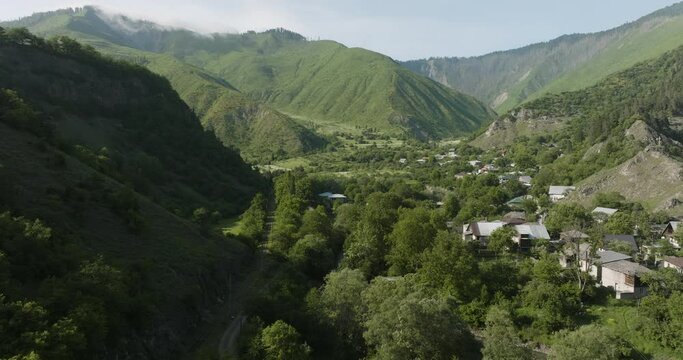 Caucasus Mountain Range With The Idyllic Townscape Of Daba In Georgia. Aerial Wide Shot