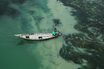 Fishermen are seen floating on top of algae as they search for potential catch in the sharp green waters of a river. The Sirajganj spot in Bangladesh is a popular place.