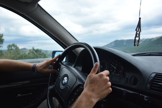 Zwei Hände eines Mannes lenken das Lenkrad eines BMW 5er e39, Blick vom Beifahrer-Sitz, Virpazar, Montenegro, 12.07.2019