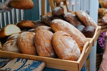 Selling freshly baked rye bread at street stall. Brown rustic bread with crust and flour. Close-up, selective focus
