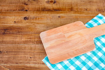 cutting board on a checkered napkin lies on a wooden table. View from above