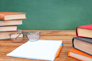 glasses, books and a notepad lie on a table on a green background