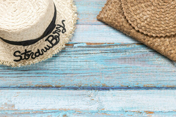 Fototapeta na wymiar A straw hat and a straw bag on the light blue wooden background. Beach and Summer concept.