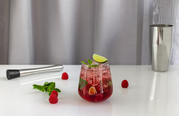 Raspberry daiquiri, alcoholic cocktail with raspberry, white rum, lime juice, and crushed ice in a glass, with steel bar tools. Summer refreshing drink.