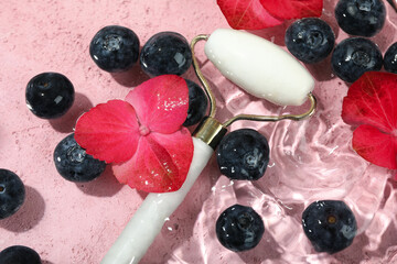 Blueberry, flowers and face roller in water