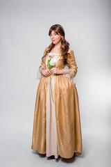 Full length portrait of a woman in a gold dress in the style of the rococo era, standing and posing...