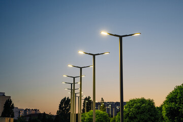 A modern street LED lighting pole. Urban electro-energy technologies. A row of street lights against the night sky - obrazy, fototapety, plakaty
