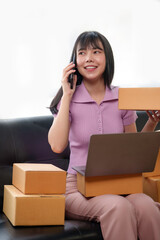 Online business owner Asian woman answering the phone talking to a customer and take note of the details of the delivery customer Negotiated address to verify correct details.