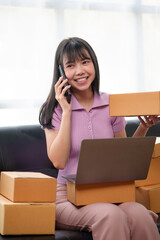 Online business owner Asian woman answering the phone talking to a customer and take note of the details of the delivery customer Negotiated address to verify correct details.