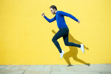 Fototapeta na wymiar young man jumping for success on a yellow background