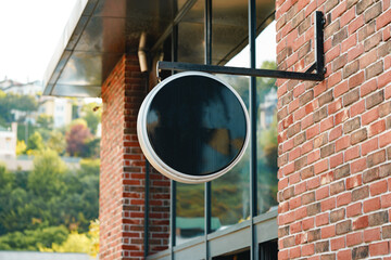 Empty black round signboard on the brick wall