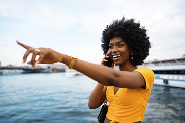 Happy young african american young woman talking with cellphone in city