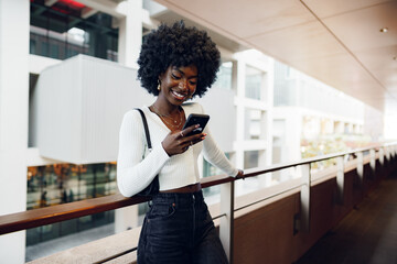Beautiful young african woman using mobile phone in the street