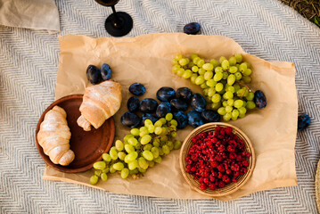 summer picnic of plums, grapes, raspberries and croissants on a blanket in nature