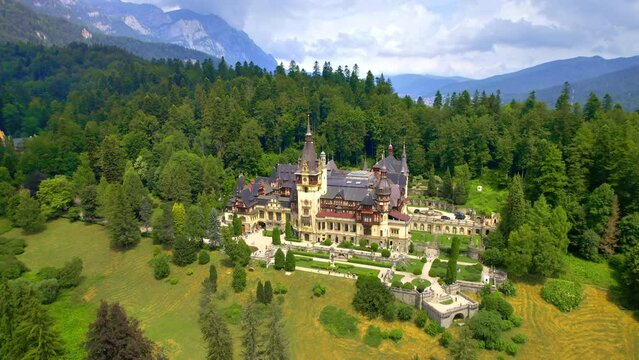Aerial drone view of The Peles Castle in Romania. Castle with gardens and tourists in Carpathians, lush forest around it