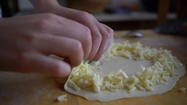 Stuffing pizza crust with cheese. Homemade pizza base dough in kitchen