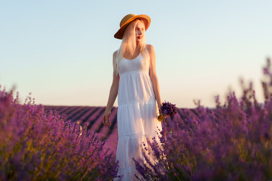 Young woman in long white dress standing in lavender field