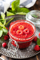 Homemade preservation. Delicious raspberries jam or jelly on a rustic wooden table.