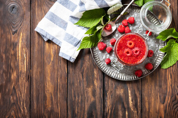 Homemade preservation. Delicious raspberries jam or jelly on a rustic wooden table. View from above. Copy space.