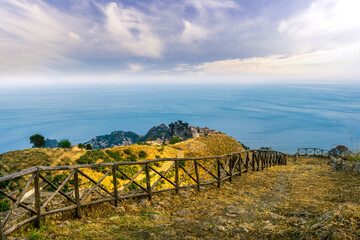 Obraz premium mountain landscape with a hiking trail leading to a mountain town and beautiful blue seashore far away