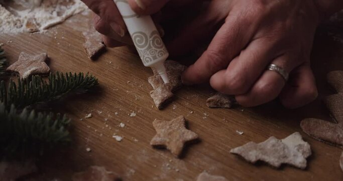 Garnishing Christmas tree shaped gingerbread cookies with icing from a tube