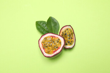 Slices of fresh ripe passion fruit (maracuya) with leaves on light green background, flat lay