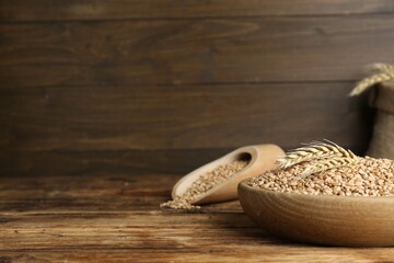 Bowl with wheat grains on wooden table