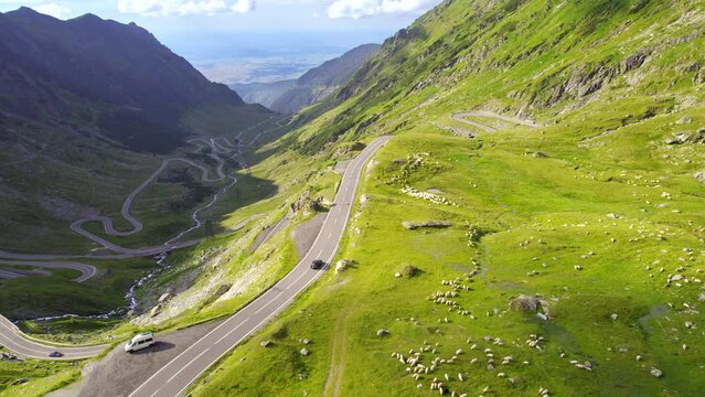 Aerial drone view of nature in Romania. Transfagarasan route in Carpathian mountains with moving cars, rocky slopes with greenery