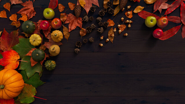 Seasonal Wallpaper, with Fall Leaves, Pumpkins and Berries on a Dark wood Surface. Thanksgiving Concept with copy space.