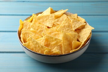 Tortilla chips (nachos) in bowl on light blue wooden table