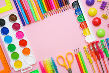 School supplies, colored pencils, watercolor paints, pens, ruler and scissors on a pink gentle...