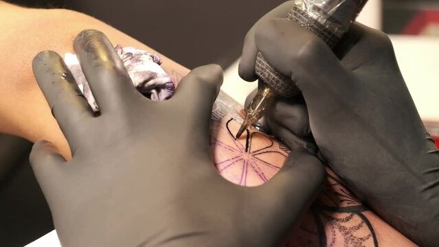 tattoo artist tattooing a tribal on an arm