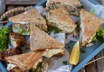 Fish cake sandwiches with cheese, lettuce and sour cream, herb sauce