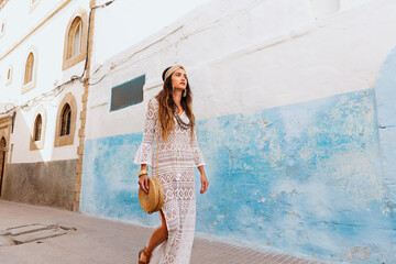 A beautiful girl in a white dress walks down the street of Essaouira. Morocco