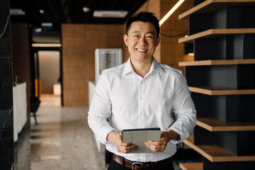 Portrait of smiling asian businessman in white shirt with tablet
