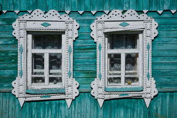 Facade of a traditional rural wooden house with ornamental painted frames with fancy carvings.