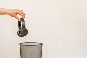 The headphones is thrown into the trash for disposal and recycling.White,gray background,selective focus,copy space.