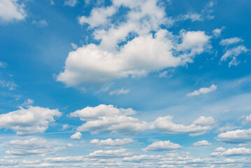 Fototapeta premium White clouds in the blue sky. White light cloudy heaven,good weather. Summer sky. Heaven and infinity. Curly clouds on a sunny day. Beautiful bright blue background.