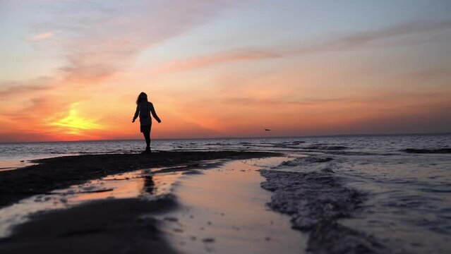 Young woman dancing on the beach against sunset sky