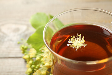 Cup of tea with linden blossom on table, closeup. Space for text