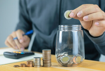 businessman holding coins putting in glass with using calculator to calculate concept saving money for finance accounting, Business, finance, investment, Financial planning.